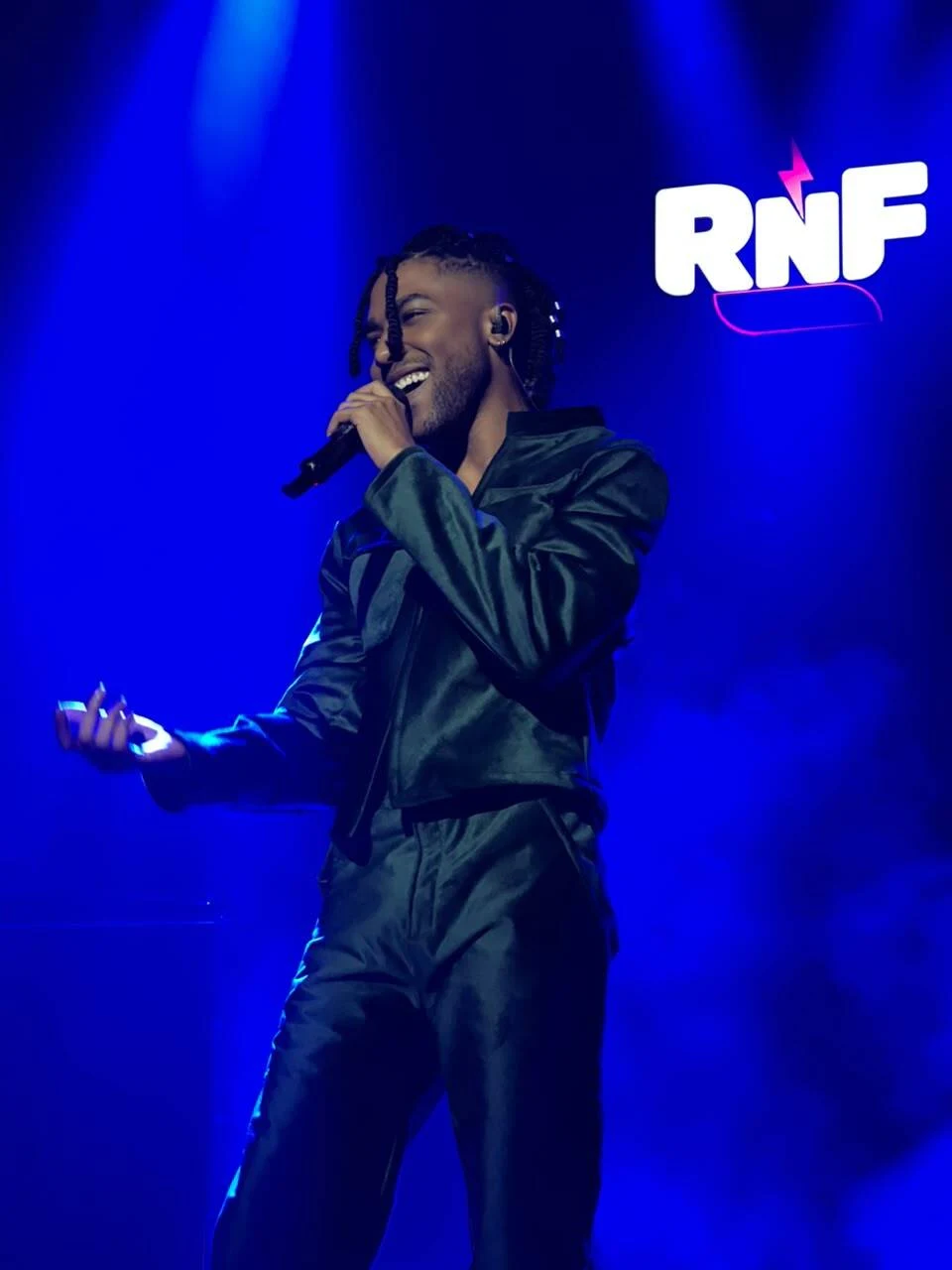 Reny Rentería cantando con un micrófono bajo luces azules