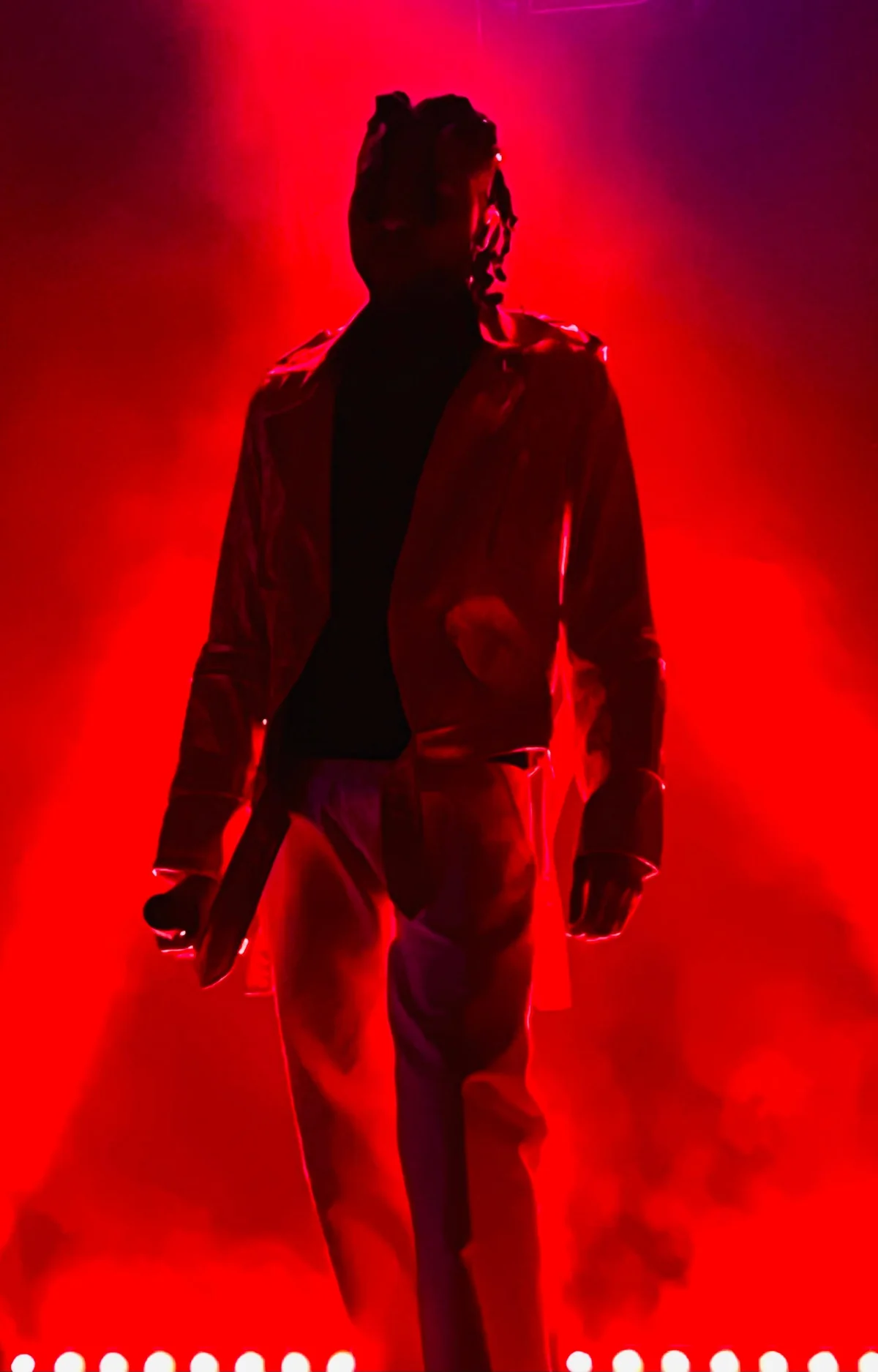 Reny Rentería en el escenario, con micrófono y luces rojas